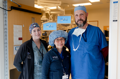 Caoimhe Duffy, Julia Tchou, and Matt Carey stand outside of an operating room